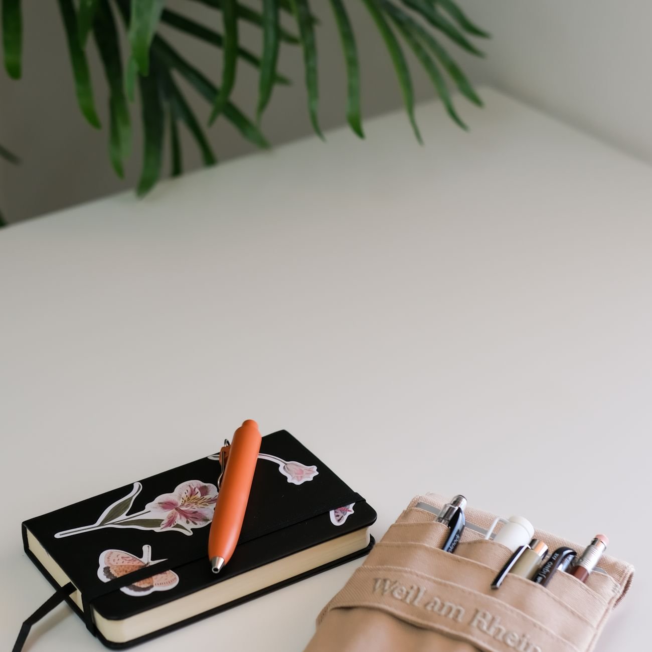 Clean minimalist workspace with branded notebook and pen on a white desk