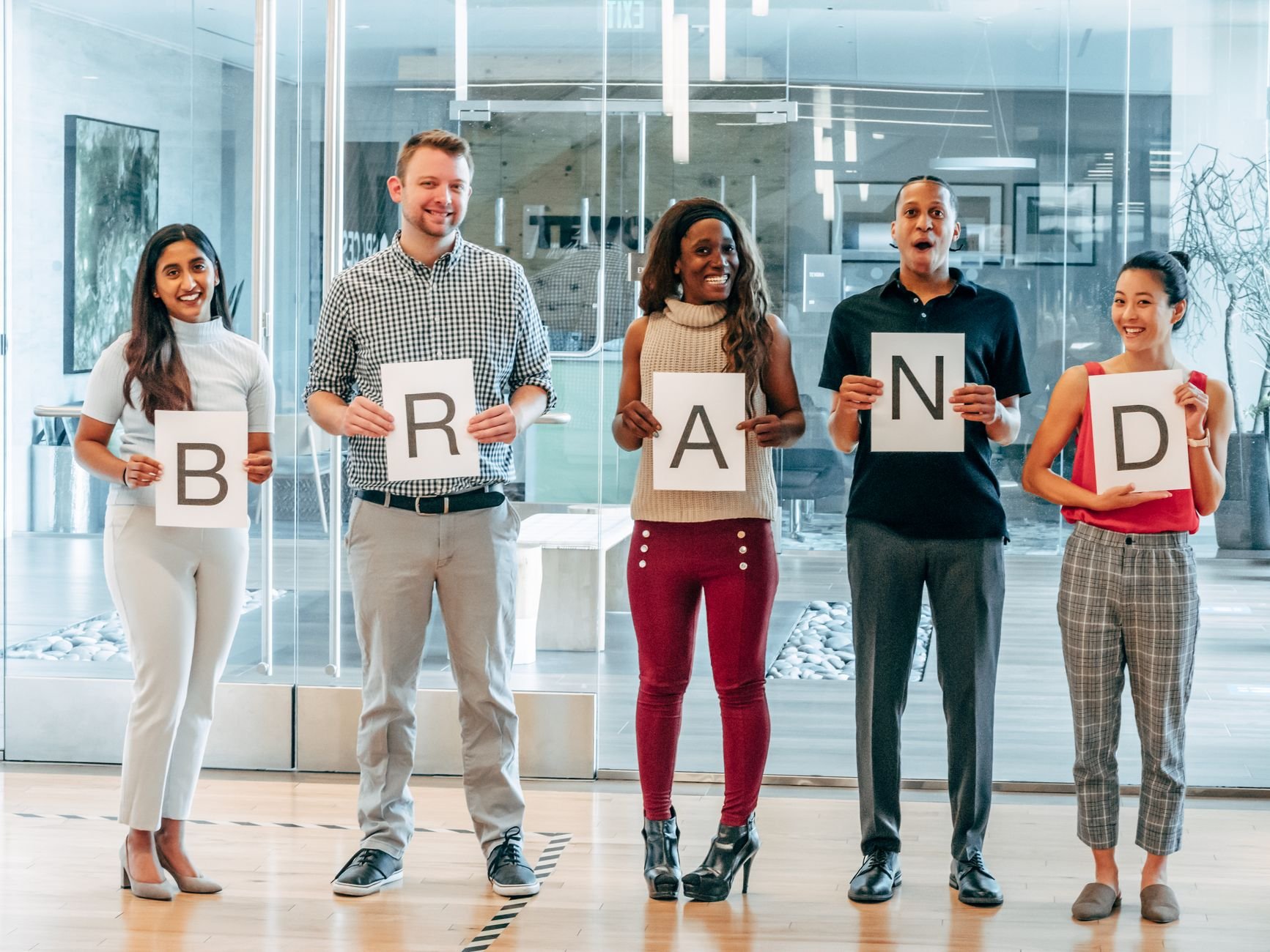 Diverse business team smiling and holding brand signs in a modern office